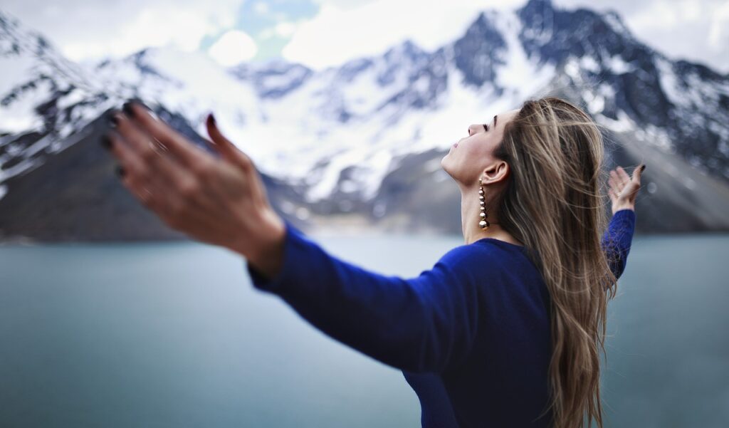 Person an einem See auf einem Berggipfel symbolisiert emotionale Freiheit und Transformation