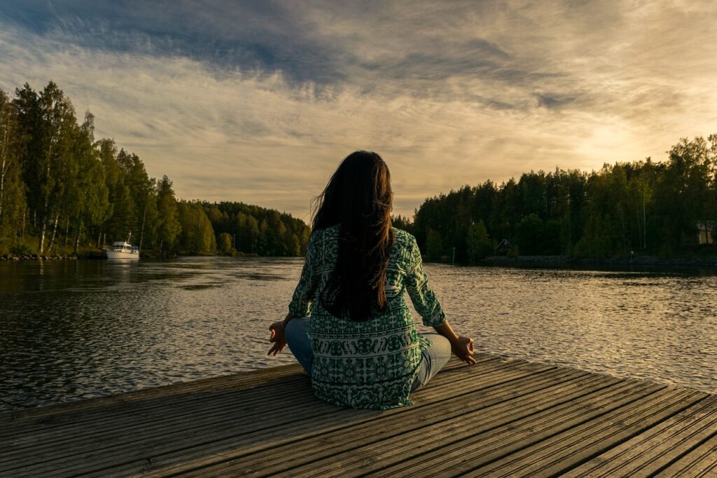 Person in Meditation am See symbolisiert emotionalen Frieden und Freiheit