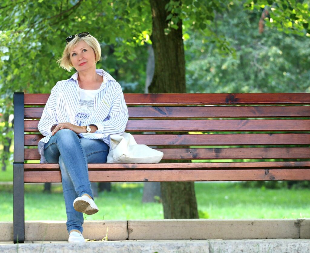 Eine nachdenkliche Frau auf einer Parkbank nach einem Yager Coaching, die über therapeutische Hilfe nachdenkt